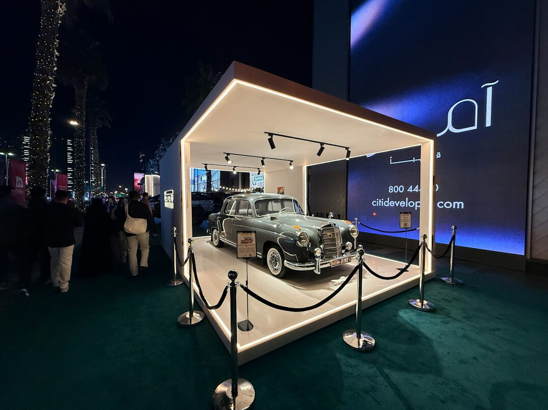 Auctioneer's podium with a rare vintage automobile displayed under spotlight