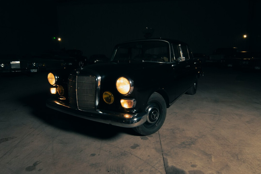 Rare vintage sports car illuminated by a single spotlight in a dark studio